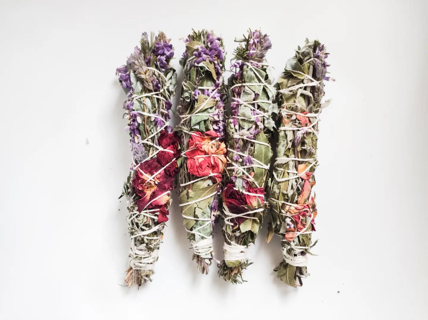 Cuatro sahumos atados con hilo, con flores secas